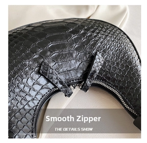 Detail of silver smooth metal zipper and crocodile embossed leather on black crescent bag