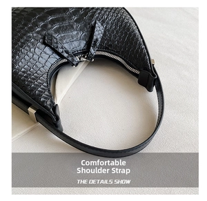 Detail shot of black crocodile pattern shoulder bag featuring silver zipper and leather strap