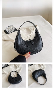 Detail view of black crescent bag with embossed crocodile pattern and zip closure