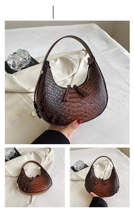 Detail of dark brown hobo bag with crocodile texture and double zipper closure