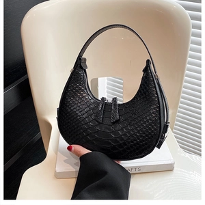 Detail of black crescent hobo bag featuring textured faux snakeskin and a smooth zipper