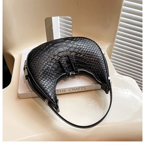 Detail of black croc-embossed crescent hobo bag with silver hardware on book prop