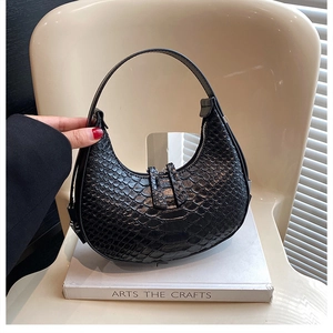 Detailed view of the black hobo bag's embossed crocodile texture and zipper closure