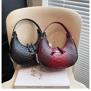 Detail of red and black crocodile embossed hobo bags on a chair with soft lighting