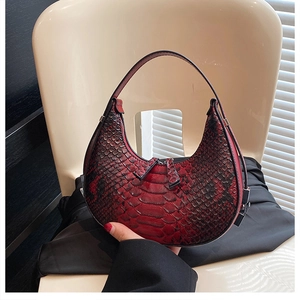 Detail of red and black snakeskin pattern on a hobo crescent bag with dual zippers