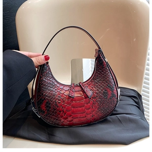 Detail of red and black snakeskin pattern on a moon-shaped hobo bag with zip puller