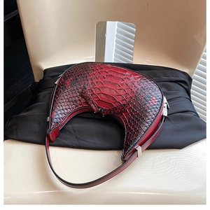 Detail of red and black snakeskin pattern on a crescent-shaped shoulder bag with silver hardware