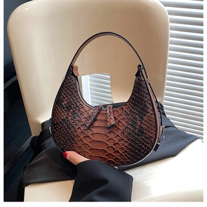 Detailed macro view of the brown snake skin texture on a crescent moon shaped shoulder bag