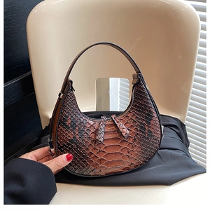 Detailed shot of a brown crocodile pattern hobo bag on a light beige artistic chair