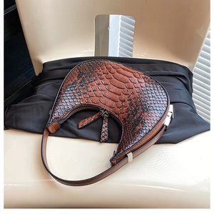 Detail of crocodile embossed hobo bag featuring a crescent shape and long leather pullers