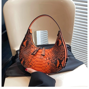Detail of orange and black snakeskin pattern on a crescent moon shaped handbag