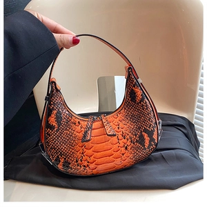 Detail of orange and black snakeskin texture on a crescent hobo handbag with dual zippers