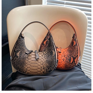 Detail view of crescent handbags in brown and orange faux snakeskin texture with metal zippers