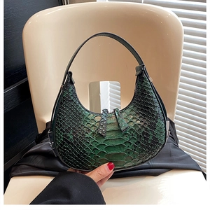 Detailed texture of dark green crocodile pattern on crescent shaped shoulder handbag