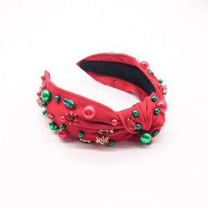 Detail of red Christmas knotted headband with green rhinestones and bow embellishments