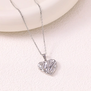 Polished silver heart-shaped hollow pendant necklace set on a minimalist background
