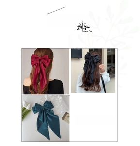 Detailed close-up of oversized satin bow hair clips in wine red, black, and dark green