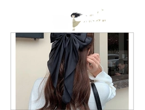 Detail of elegant black satin bow hair clip with long ribbons on model back head
