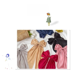 Close-up of oversized satin bow hair clips in multiple colors on a textured surface