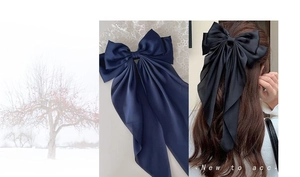 Detail of navy blue oversized satin bow hair clip with long ribbons worn on hair