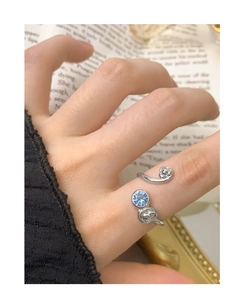 Detail of silver S925 ring with blue zircon and rose carvings on an open band