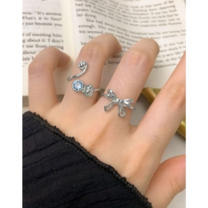 S925 silver adjustable rings set with blue zircon and floral bow design on a book