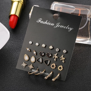 Golden earrings set with vintage stars and pearls on display card in a professional setting