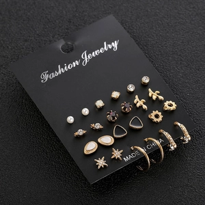 Golden multi-piece earring set featuring pearls and crystals on a black display card