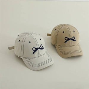 Dettaglio di cappelli da baseball per bambini con ricamo a fiocco blu e cuciture a contrasto