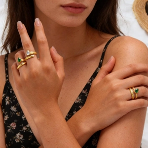 Detail of gold twisted rope rings with emerald and clear pear-cut stones on hand