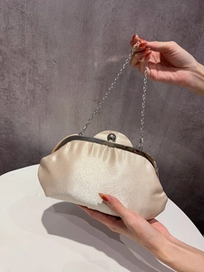 Close-up of champagne satin evening bag with pleated clouds design and metal kiss lock