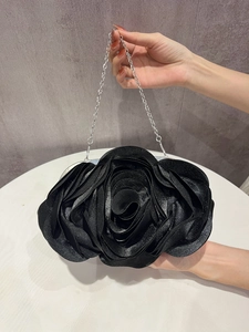 Detail of elegant black rose-shaped evening clutch bag with sparkling 3D petal texture