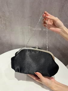 Close-up of black glitter evening clutch with silver metal frame and chain strap