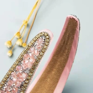 Macro detail of pink satin headband featuring crystal floral beadwork and velvet lining