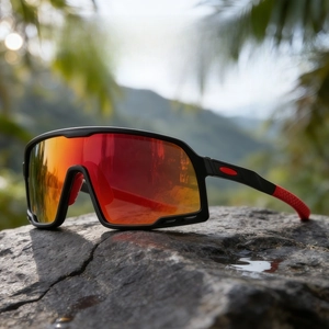 Detail of red mirrored sports sunglasses resting on a dark rock with blurred mountain views