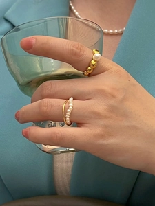Close-up of vintage style 18K gold plated freshwater pearl rings worn by a model