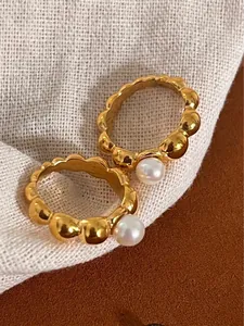 Set of two vintage gold bubble rings featuring elegant freshwater pearls on a linen base