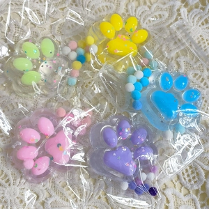 Five colorful cat paw stress relief toys with star glitter and fuzzy balls in packaging