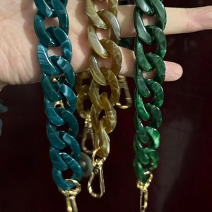 Detail of acrylic fishbone chains in amber, emerald, and blue with gold metal clasps