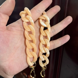Detail of almond acrylic resin bag chain with white marble texture and gold lobster clasp