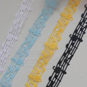 Macro detail of musical note lace ribbons in white, blue, yellow, and black colors