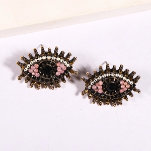 Detailed view of evil eye earrings featuring antique gold finish and pink crystal accents