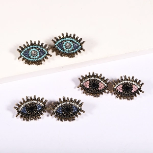 Close-up of three pairs of colorful evil eye earrings with bohemian crystal accents