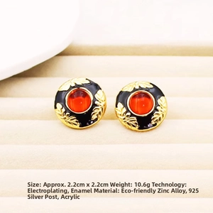 Detail view of vintage round earrings with black enamel, red stone, and gold plating