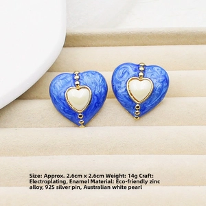Macro detail of blue enamel heart earrings with white pearl inlay and 2.6cm dimensions