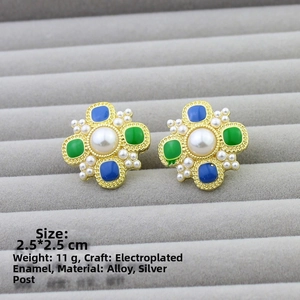 Macro shot of vintage cross earrings with faux pearls and blue green enamel detailing