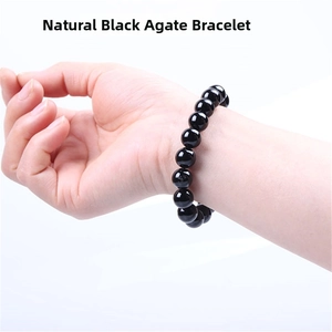 Close-up of a natural black agate bracelet with polished beads on a person's wrist