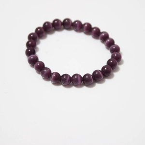 Macro detail of natural purple cat eye stone beads on a polished round beaded bracelet