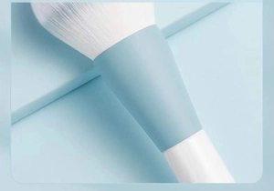 Close-up of dense white synthetic bristles and light blue ferrule on makeup brush