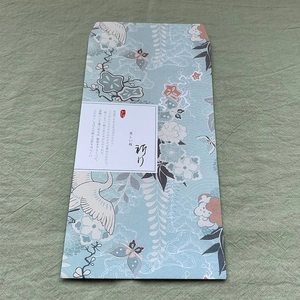 Detail of traditional Japanese envelope with crane patterns on green linen texture